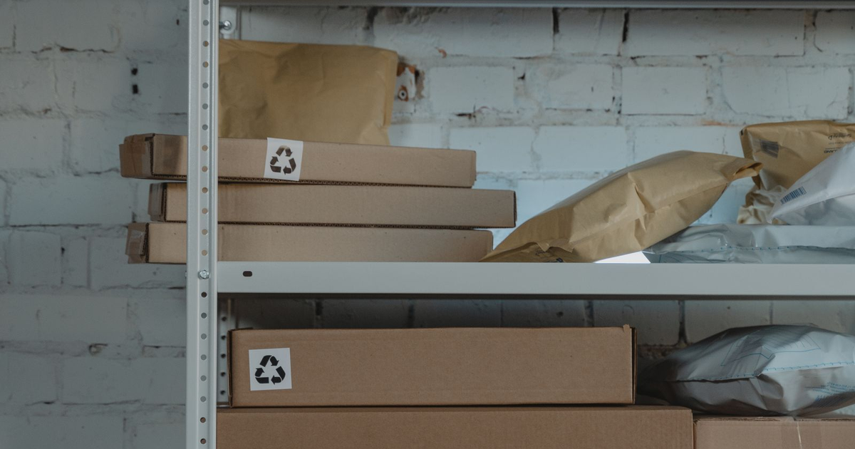 Cardboard shipping boxes and mailers on a warehouse shelf.